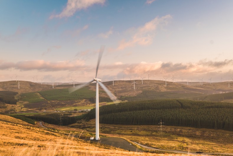 Onshore wind turbines at the Clyde wind farm as the sun sets, creating a nice golden glow over the scene.